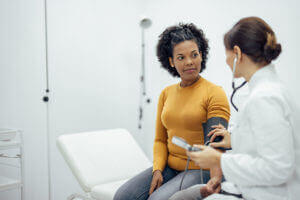 Primary Care Doctor measuring woman's blood pressure