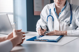 Family Doctor writing a medical prescription to patient