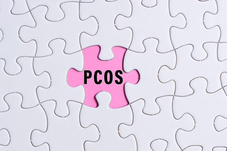 PCOS text on white jigsaw puzzle over pink background