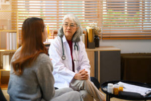 A senior female family doctor is listening to her female patient during a session in her primary care office.