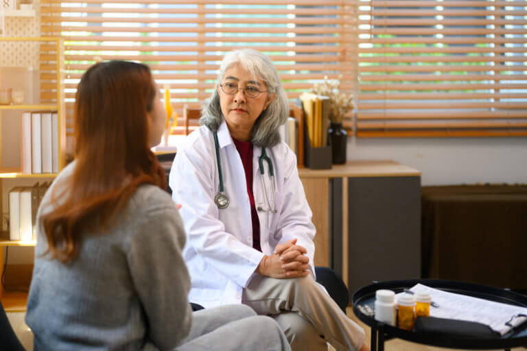 A senior female family doctor is listening to her female patient during a session in her primary care office.