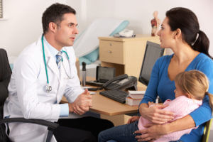 A family practice doctor is talking to a worried mother and her child.