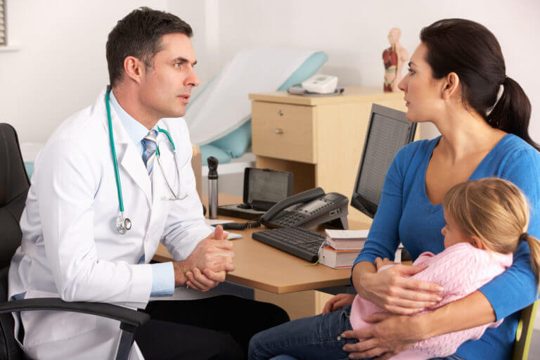 A family practice doctor is talking to a worried mother and her child.
