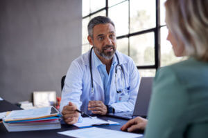 A male primary care doctor consulting with a patient during a doctor's appointment.