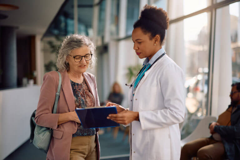 A senior woman and her primary care physician are discussing over a medical test results at the clinic.