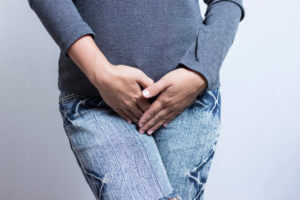 A woman with her hands holding her lower part of the body due to frequent UTIs.