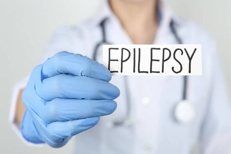 A neurologist who specializes in epilepsy treatment is holding card with word Epilepsy on light grey background.