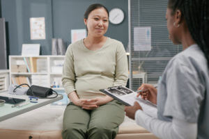 Pregnant Young Adult Asian Woman Smiling during Consultation with an Obstetrician-Gynecologist.