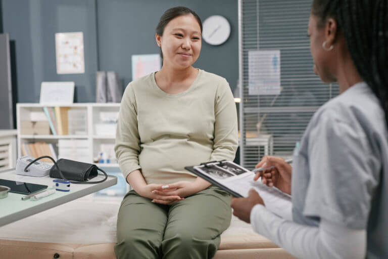 Pregnant Young Adult Asian Woman Smiling during Consultation with an Obstetrician-Gynecologist.