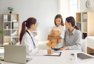 Happy mother and little daughter talking to their family medicine practitioner at the clinic.