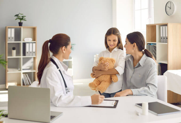 Happy mother and little daughter talking to their family medicine practitioner at the clinic.